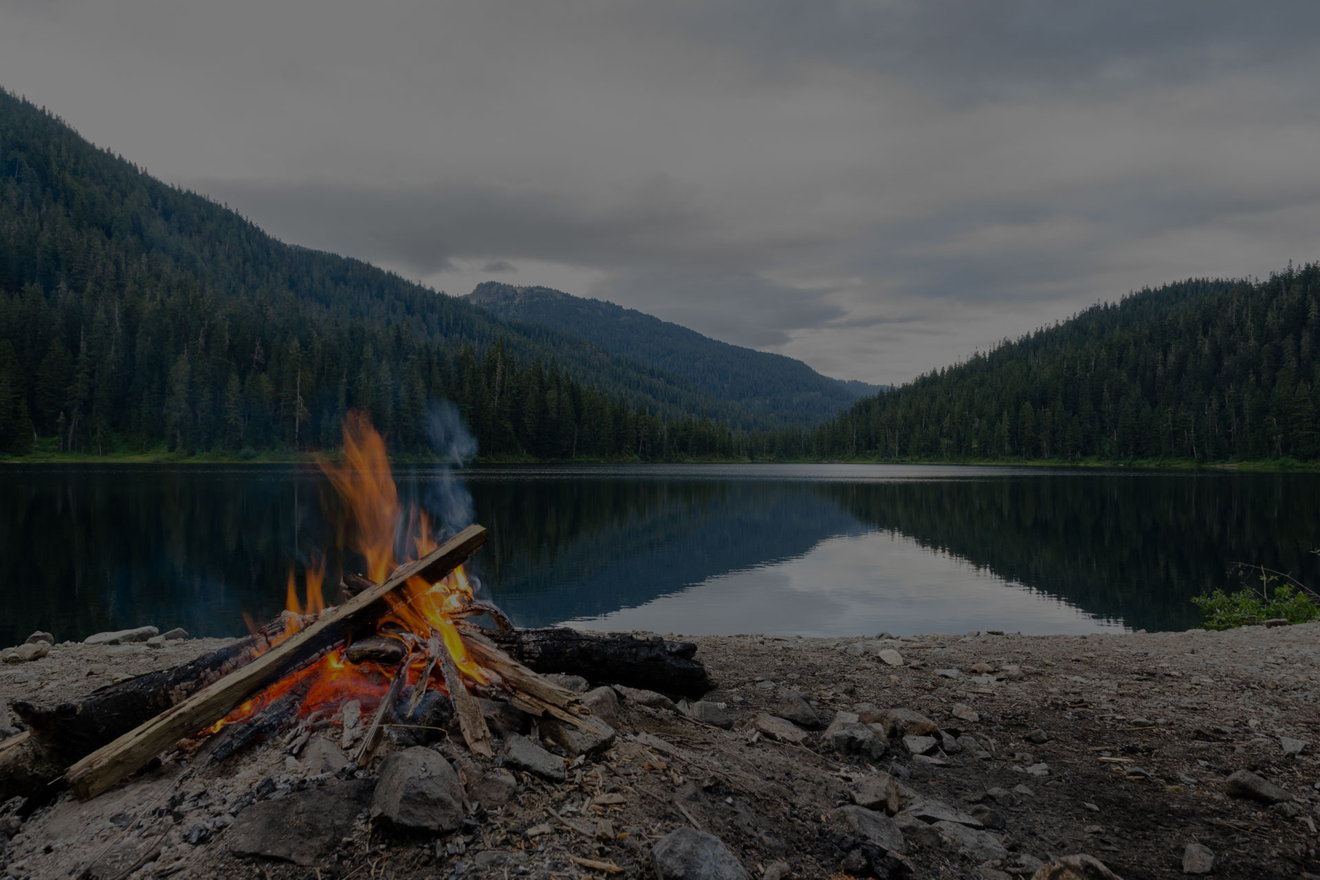 Landscape of a campfire in a peaceful lake valley.